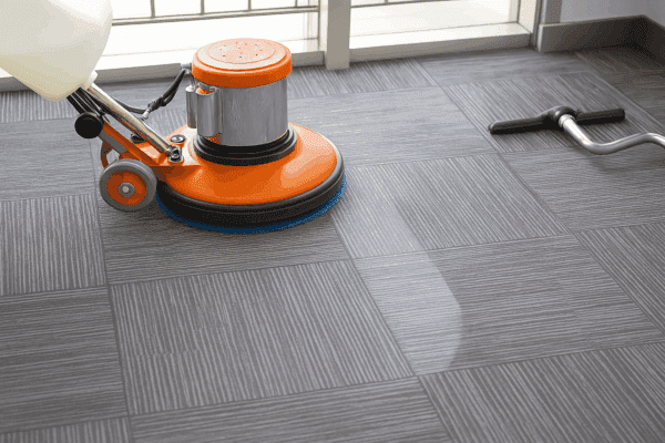 Pracownik Ekomilo podczas prania wykładzin Warszawa rotacyjną maszyną